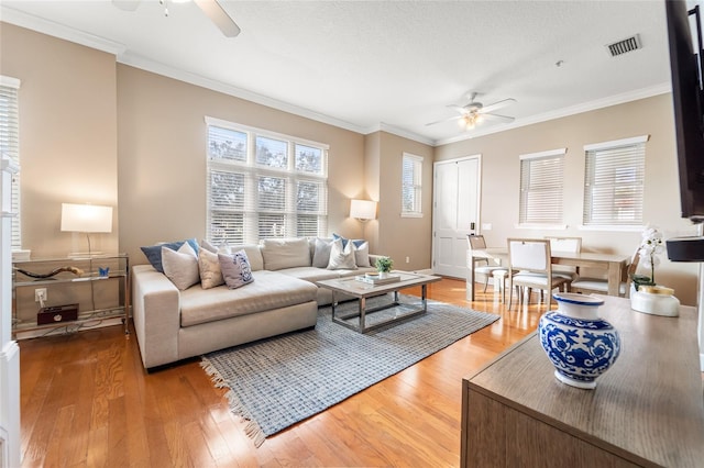 living room featuring wood-type flooring, ornamental molding, and ceiling fan