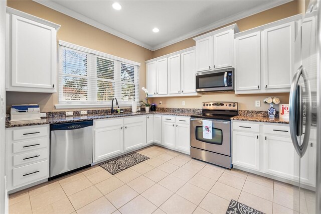 kitchen with white cabinetry, stainless steel appliances, sink, and dark stone countertops