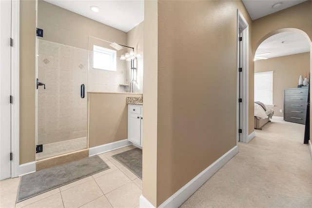 bathroom with a shower with door, vanity, and tile patterned floors