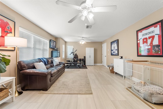 living room featuring ceiling fan and a textured ceiling