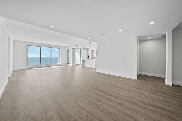 unfurnished living room featuring hardwood / wood-style flooring and a water view