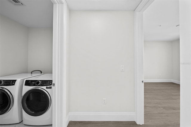 washroom featuring light hardwood / wood-style flooring and washing machine and clothes dryer