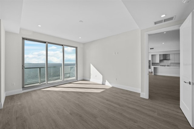 spare room featuring a water view and dark wood-type flooring