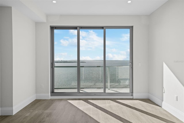 spare room with wood-type flooring, a wealth of natural light, and a water view