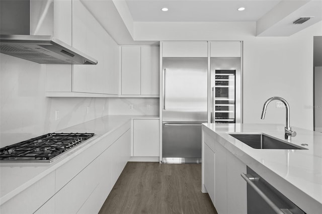 kitchen featuring stainless steel appliances, white cabinetry, and wall chimney range hood