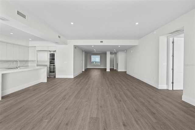 unfurnished living room featuring wood-type flooring and sink