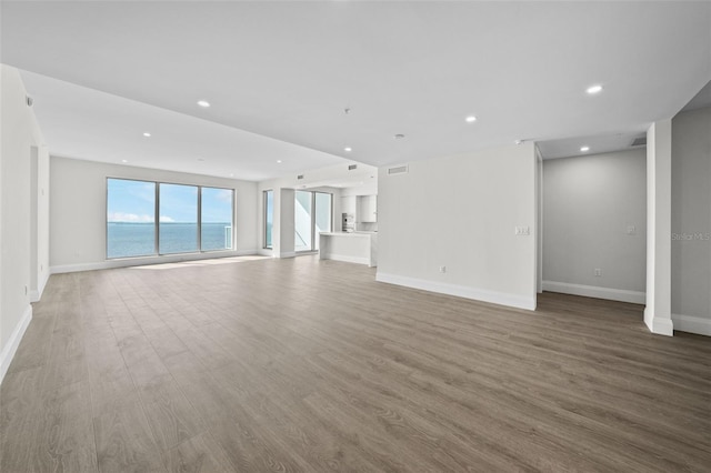 unfurnished living room with a water view and hardwood / wood-style flooring