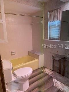 bathroom featuring hardwood / wood-style floors, a tub, and toilet