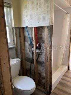 bathroom with toilet, a shower with shower curtain, and hardwood / wood-style floors