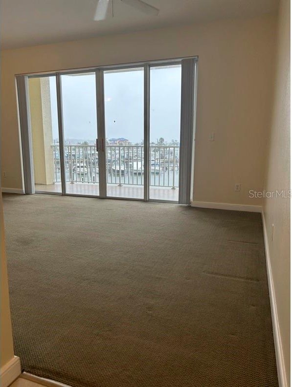 carpeted spare room with a wealth of natural light, ceiling fan, and a water view