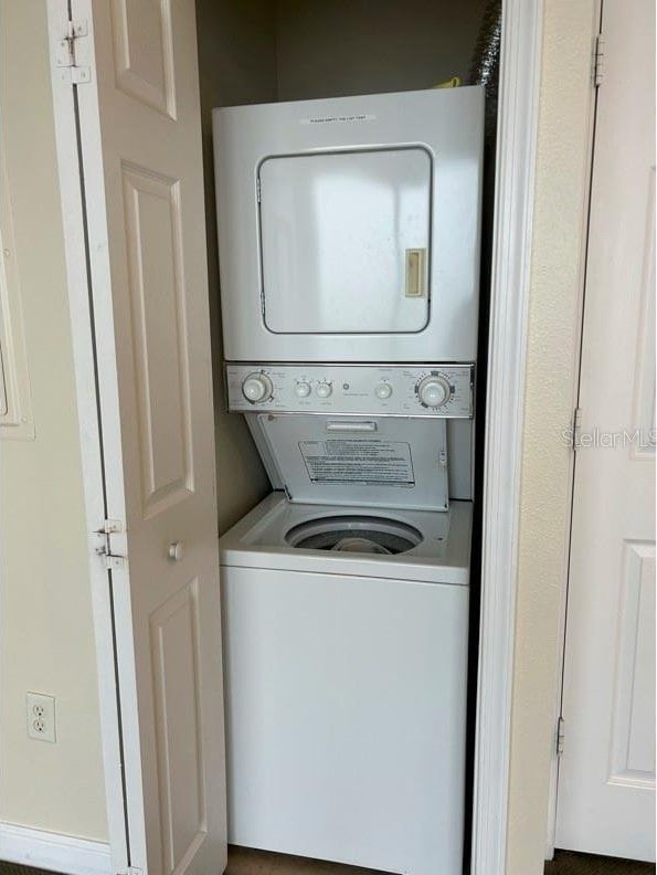 clothes washing area with stacked washing maching and dryer