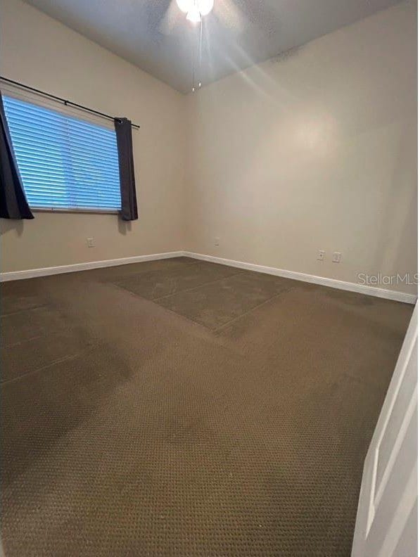 spare room with a textured ceiling and dark colored carpet