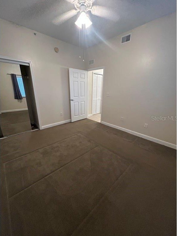 carpeted empty room featuring ceiling fan and a textured ceiling