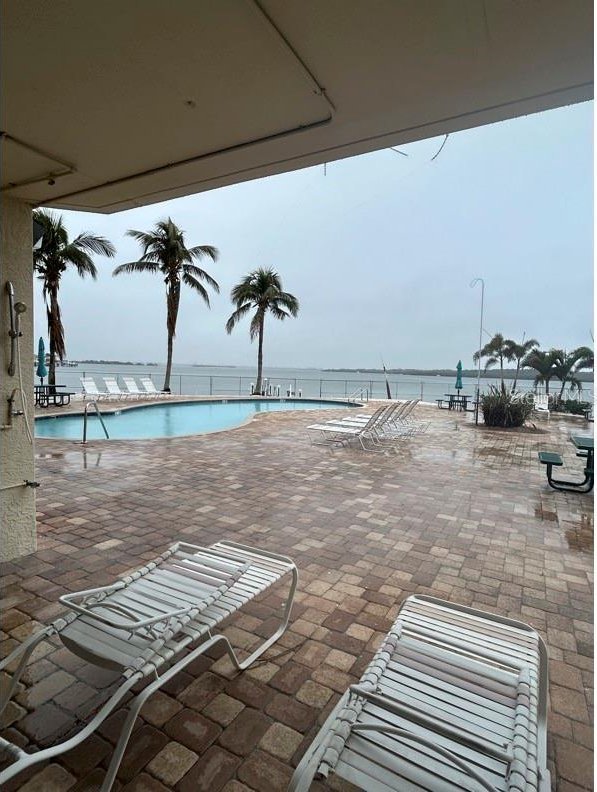 view of swimming pool with a water view and a patio area