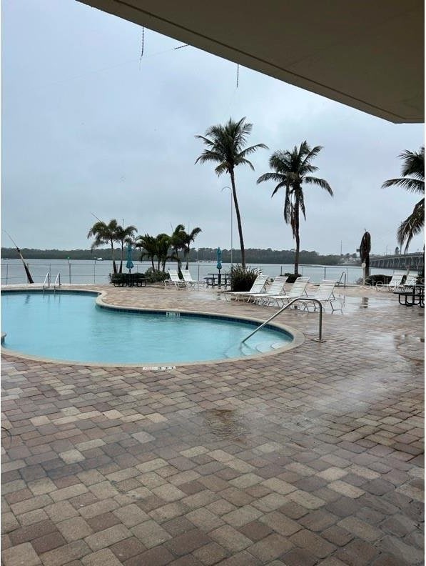 view of pool with a water view and a patio area