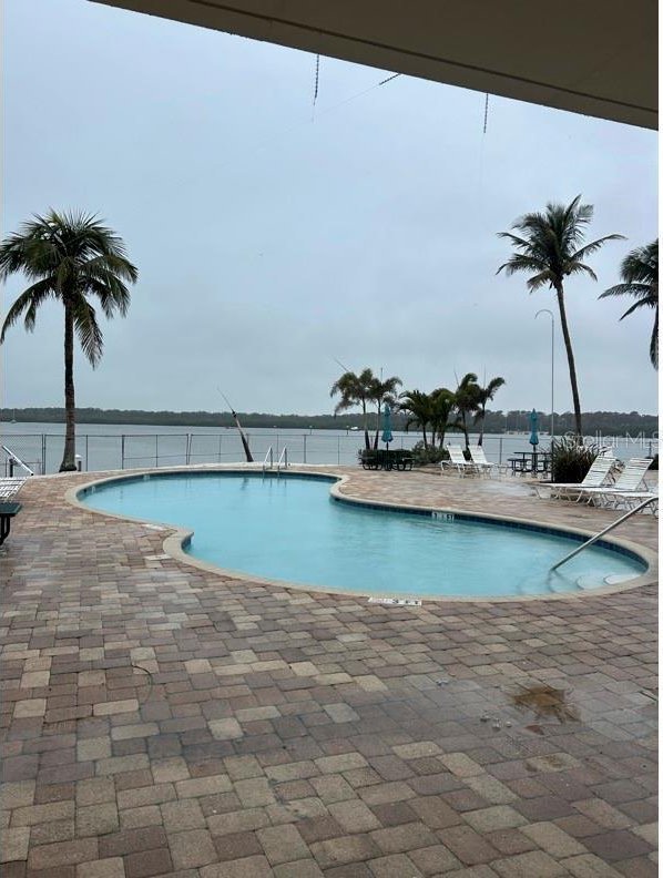 view of swimming pool with a water view and a patio