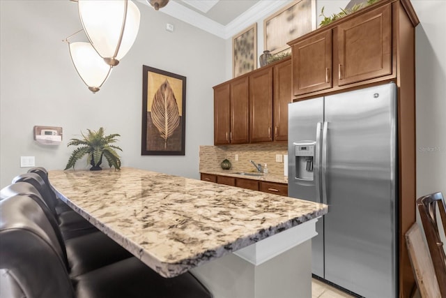 kitchen featuring stainless steel fridge with ice dispenser, hanging light fixtures, sink, kitchen peninsula, and a breakfast bar