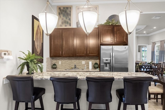 kitchen with kitchen peninsula, stainless steel fridge, sink, tasteful backsplash, and light stone counters