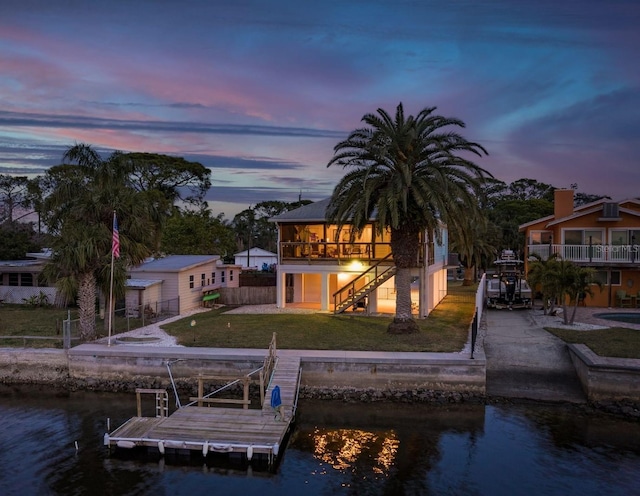 back house at dusk featuring a yard, a sunroom, and a water view