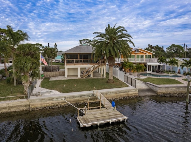 view of dock featuring a water view, a patio area, and a lawn