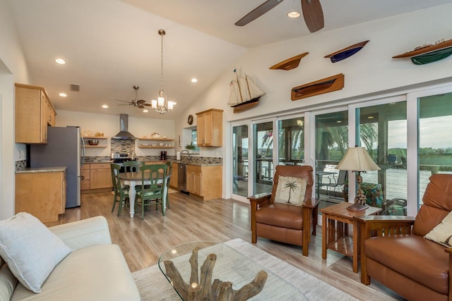 living room with ceiling fan with notable chandelier, a wealth of natural light, sink, and light wood-type flooring