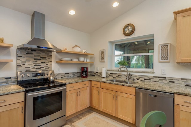 kitchen featuring lofted ceiling, sink, appliances with stainless steel finishes, ventilation hood, and light stone countertops