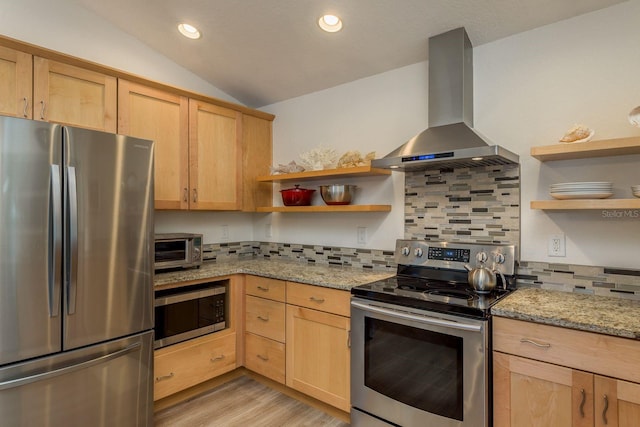 kitchen featuring light stone counters, appliances with stainless steel finishes, vaulted ceiling, and exhaust hood