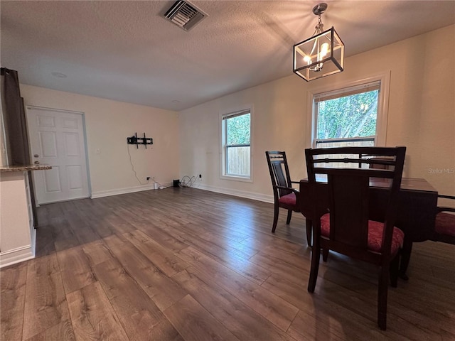 dining area with dark hardwood / wood-style floors, a textured ceiling, and an inviting chandelier