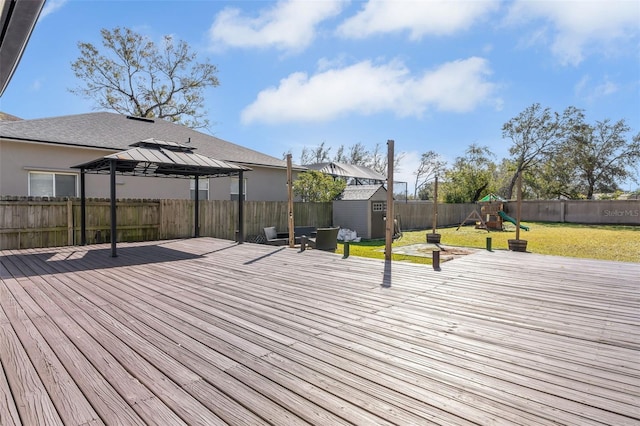 wooden deck featuring a storage shed, a gazebo, a yard, and a playground