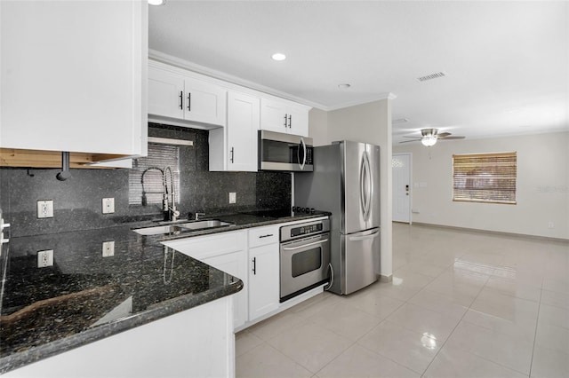 kitchen with appliances with stainless steel finishes, sink, decorative backsplash, and white cabinets