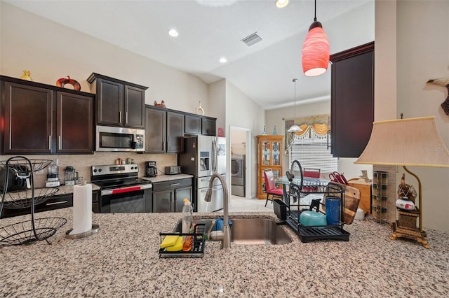 kitchen with pendant lighting, washer / dryer, appliances with stainless steel finishes, and lofted ceiling