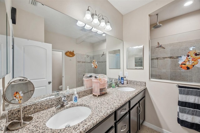 bathroom featuring toilet, vanity, and a tile shower