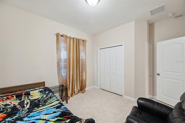 bedroom featuring light colored carpet, a textured ceiling, and a closet