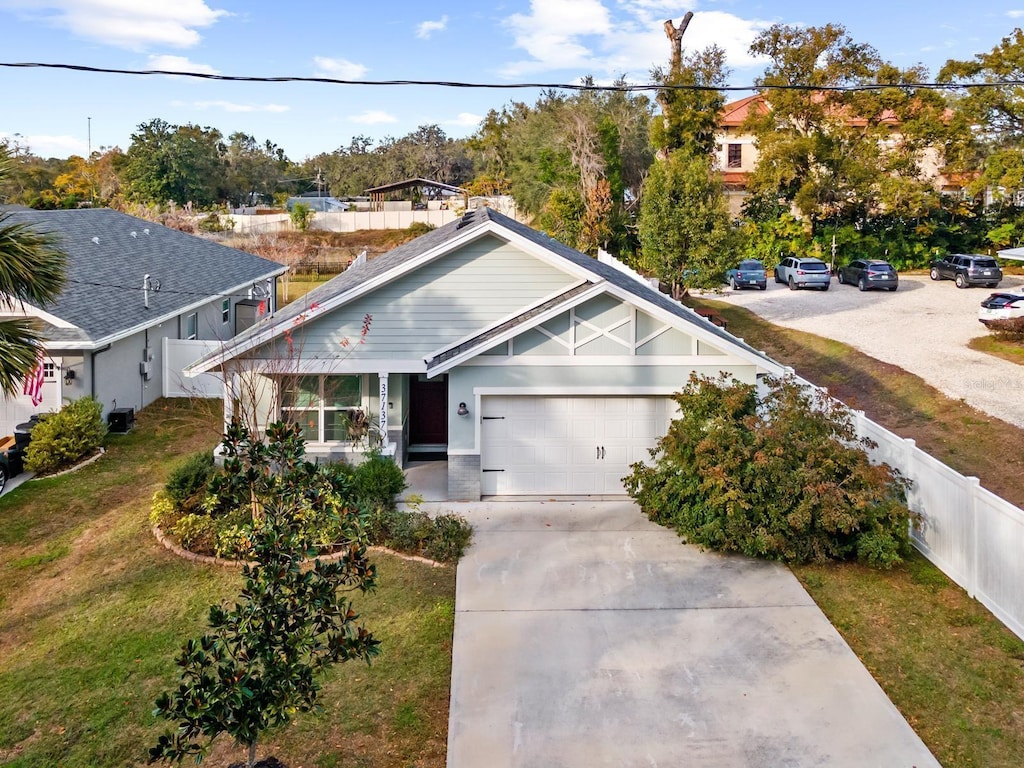 view of front of house featuring a garage, central air condition unit, and a front lawn