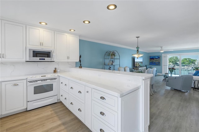 kitchen featuring white appliances, decorative light fixtures, kitchen peninsula, and white cabinets