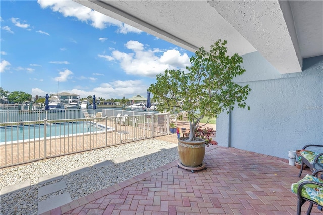 view of patio / terrace featuring a water view and a fenced in pool