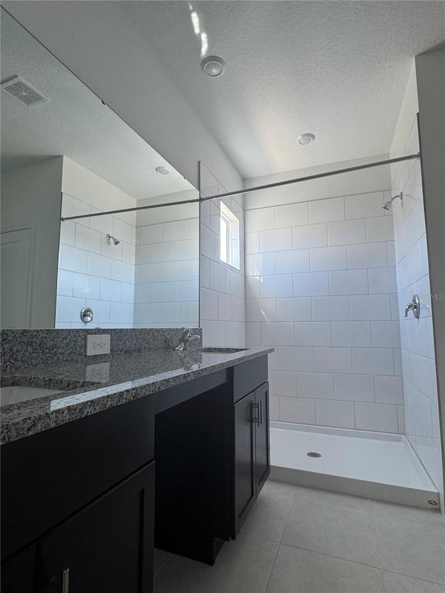 bathroom featuring tiled shower, vanity, tile patterned flooring, and a textured ceiling