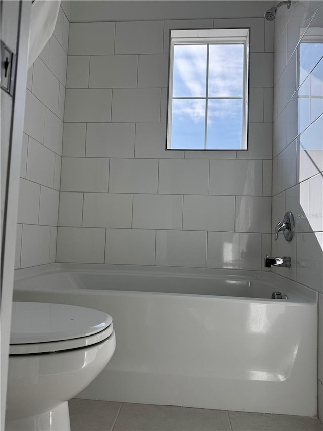 bathroom with tile patterned flooring, toilet, and tiled shower / bath