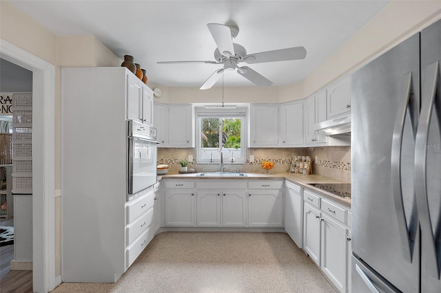 kitchen featuring sink, appliances with stainless steel finishes, white cabinets, ceiling fan, and backsplash