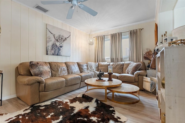 living room featuring ceiling fan, ornamental molding, and light hardwood / wood-style flooring