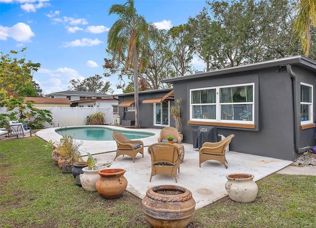 back of property featuring a fenced in pool, a patio, and a lawn