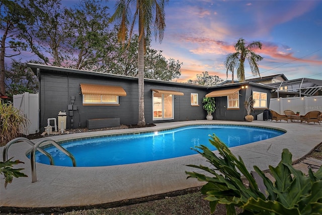 pool at dusk featuring a patio area