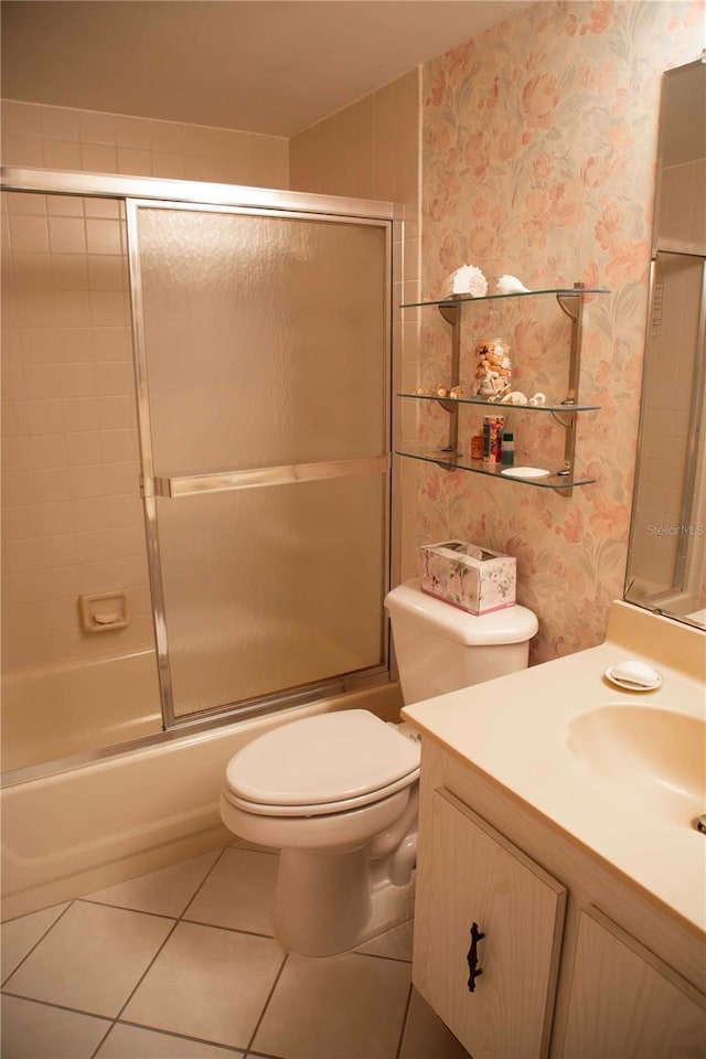 full bath with bath / shower combo with glass door, wallpapered walls, toilet, vanity, and tile patterned floors