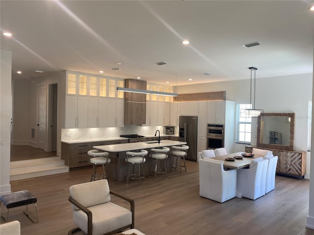 kitchen featuring pendant lighting, stainless steel appliances, dark hardwood / wood-style floors, and a center island with sink