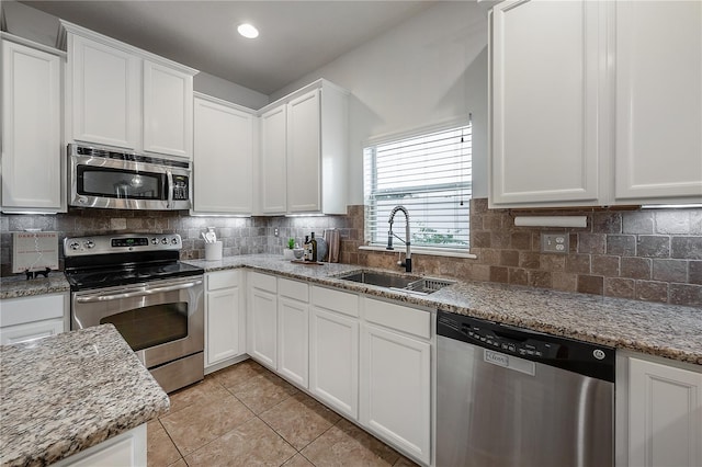 kitchen featuring stainless steel appliances, light stone countertops, sink, and white cabinets