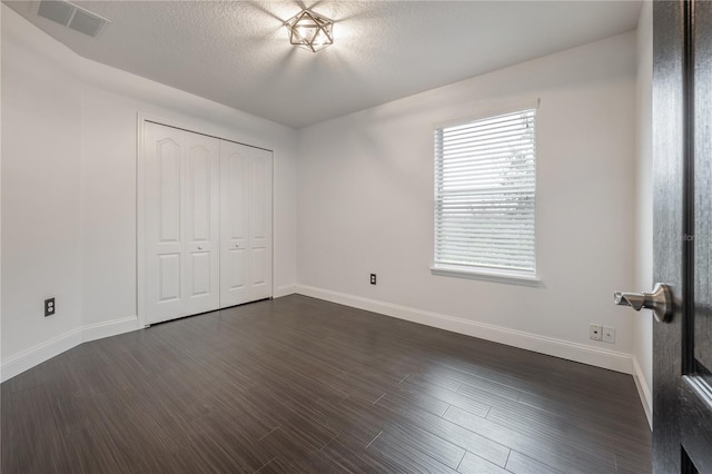 unfurnished bedroom featuring dark hardwood / wood-style floors, a closet, and a textured ceiling