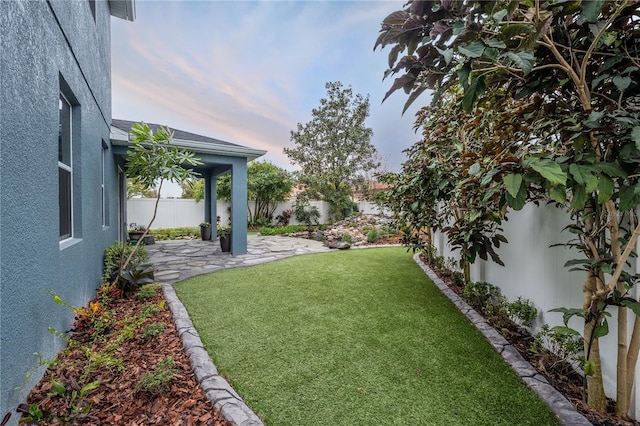 yard at dusk featuring a patio area