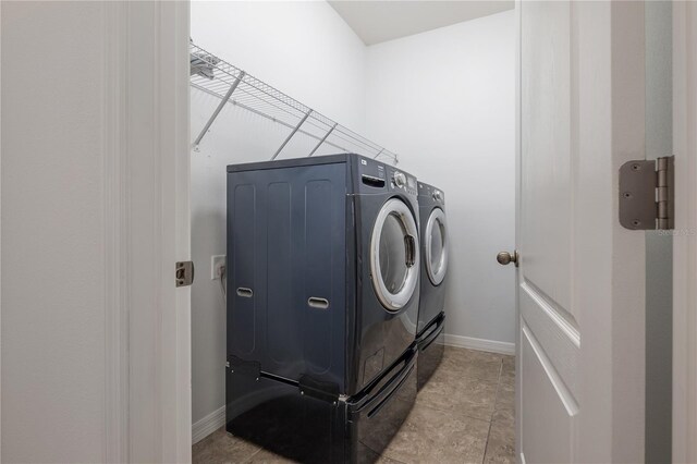 laundry area with light tile patterned flooring and washer and clothes dryer