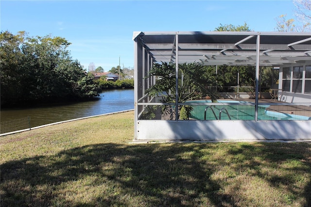 view of swimming pool with glass enclosure, a water view, and a yard