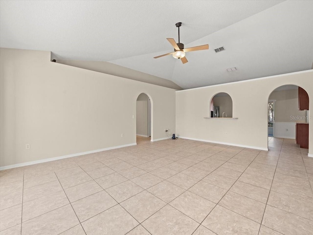 tiled empty room with ceiling fan and vaulted ceiling